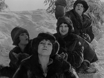 Movie still from “The Gold Rush” (1925), directed by Charles Chaplin – A group of women in fur coats sitting in the snow; Medium shot, Low angle