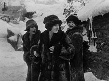 Movie still from “The Gold Rush” (1925), directed by Charles Chaplin – A group of three women in fur coats and hats; Medium shot, High angle