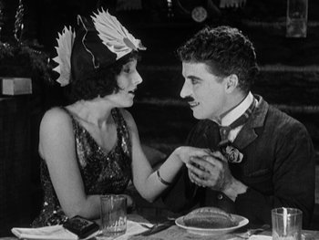 Movie still from “The Gold Rush” (1925), directed by Charles Chaplin – A man and a woman sitting at a dinner table; Medium shot, High angle
