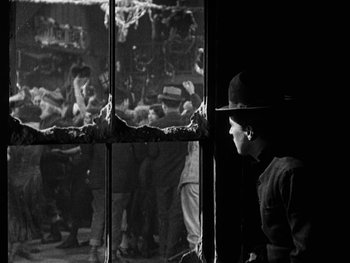 Movie still from “The Gold Rush” (1925), directed by Charles Chaplin – An old photo of a woman looking out a window; Medium shot, Over the shoulder angle