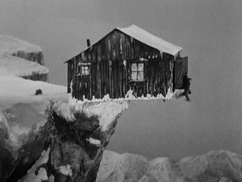 Movie still from “The Gold Rush” (1925), directed by Charles Chaplin – A black and white photo of a cabin in the snow; Extreme Wide shot, High angle