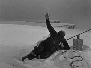 Movie still from “The Gold Rush” (1925), directed by Charles Chaplin – A man falling down in the middle of a snow covered field; Wide shot, High angle