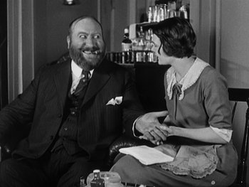 Movie still from “The Gold Rush” (1925), directed by Charles Chaplin – An old photo of a man and a woman sitting in a chair; Medium shot, Low angle