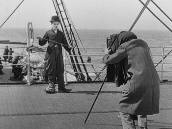 Movie still from “The Gold Rush” (1925), directed by Charles Chaplin – A man is taking a picture of another man on a boat; Medium shot, Low angle