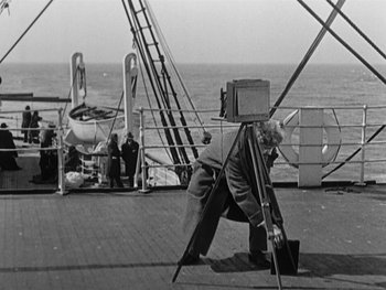 Movie still from “The Gold Rush” (1925), directed by Charles Chaplin – An old photo of a man on a boat taking a picture; Wide shot, Low angle