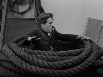 Movie still from “The Gold Rush” (1925), directed by Charles Chaplin – An old photo of a man sitting in a boat; Wide shot, High angle