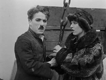 Movie still from “The Gold Rush” (1925), directed by Charles Chaplin – A man and a woman holding onto a rope; Medium shot, High angle