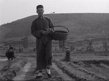 Movie still from “The Good Earth” (1937), directed by Sidney Franklin – A man holding a basket while standing in a field; Wide shot, Low angle