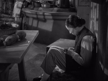 Movie still from “The Good Earth” (1937), directed by Sidney Franklin – A woman sitting on a bench looking at her cell phone; Medium shot, High angle