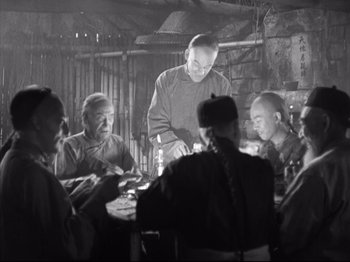 Movie still from “The Good Earth” (1937), directed by Sidney Franklin – A group of people sitting around a table; Medium shot, High angle