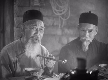 Movie still from “The Good Earth” (1937), directed by Sidney Franklin – Two old men sitting at a table with a bowl of food; Medium shot, Low angle