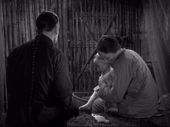 Movie still from “The Good Earth” (1937), directed by Sidney Franklin – A woman holding a baby while sitting next to a man; Medium shot, High angle