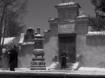 Movie still from “The Good Earth” (1937), directed by Sidney Franklin – An old photo of a man standing in front of a building; Extreme Wide shot, Low angle