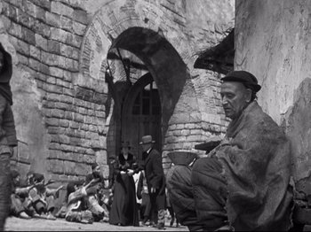 Movie still from “The Good Earth” (1937), directed by Sidney Franklin – An old man sitting in front of an old brick building; Wide shot, Low angle