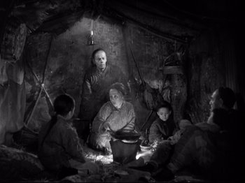 Movie still from “The Good Earth” (1937), directed by Sidney Franklin – A group of people sitting around a fire in a tent; Wide shot, High angle