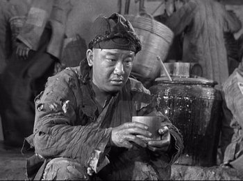 Movie still from “The Good Earth” (1937), directed by Sidney Franklin – An old photo of a man holding a cup in his hands; Medium shot, High angle