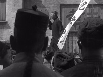 Movie still from “The Good Earth” (1937), directed by Sidney Franklin – A man standing in front of a group of people; Medium shot, Low angle