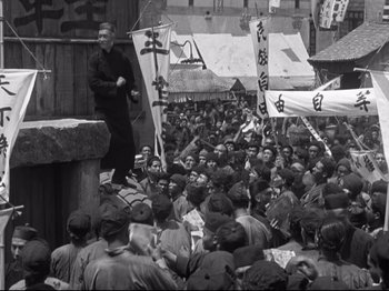 Movie still from “The Good Earth” (1937), directed by Sidney Franklin – A large group of people are gathered together in the street; Wide shot, High angle