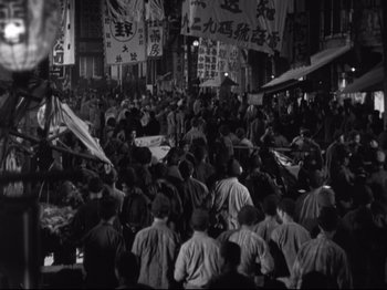 Movie still from “The Good Earth” (1937), directed by Sidney Franklin – A group of people standing in the middle of a street; Extreme Wide shot, High angle