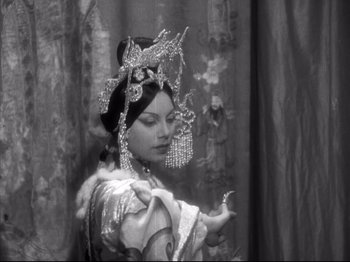 Movie still from “The Good Earth” (1937), directed by Sidney Franklin – A woman in a costume is holding a bird in her hand; Medium shot, Over the shoulder angle