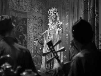 Movie still from “The Good Earth” (1937), directed by Sidney Franklin – A woman dressed as a chinese princess in a stage show; Medium shot, Over the shoulder angle