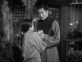 Movie still from “The Good Earth” (1937), directed by Sidney Franklin – A man and a woman holding each others hands in front of a building; Medium shot, Low angle