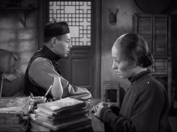 Movie still from “The Good Earth” (1937), directed by Sidney Franklin – A man and a woman are sitting at a table; Medium shot, High angle