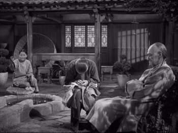 Movie still from “The Good Earth” (1937), directed by Sidney Franklin – A group of people sitting in a room; Wide shot, High angle