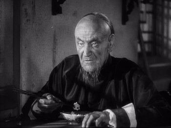 Movie still from “The Good Earth” (1937), directed by Sidney Franklin – An old man sitting at a table with a plate of food; Close Up shot, High angle