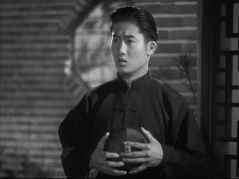 Movie still from “The Good Earth” (1937), directed by Sidney Franklin – A young man holding a box in his hands; Medium shot, High angle