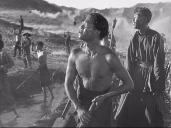 Movie still from “The Good Earth” (1937), directed by Sidney Franklin – A group of men standing on top of a sandy beach; Medium shot, Low angle