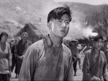 Movie still from “The Good Earth” (1937), directed by Sidney Franklin – A man in a field with other men in the background; Close Up shot, Low angle