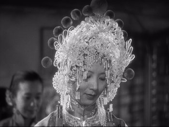 Movie still from “The Good Earth” (1937), directed by Sidney Franklin – A black and white photo of a woman wearing a headdress; Close Up shot, Over the shoulder angle