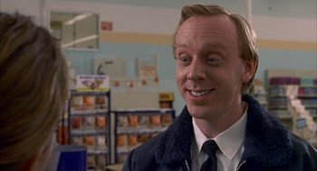 Movie still from “The Good Girl” (2002), directed by Miguel Arteta – A man in a black jacket is smiling for the camera; Close Up shot, Over the shoulder angle