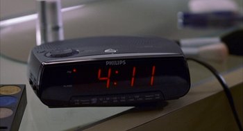 Movie still from “The Good Girl” (2002), directed by Miguel Arteta – A black alarm clock sitting on top of a wooden table; Extreme Close Up shot, High angle