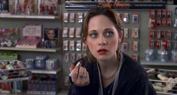 Movie still from “The Good Girl” (2002), directed by Miguel Arteta – A woman is holding a lipstick in her hand; Close Up shot, Over the shoulder angle
