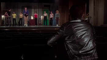 Movie still from “The Goodbye Girl” (1977), directed by Herbert Ross – A group of people standing on a stage in front of an audience; Wide shot, Over the shoulder angle