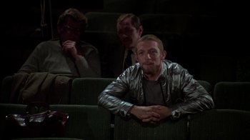 Movie still from “The Goodbye Girl” (1977), directed by Herbert Ross – A man sitting in a theater with two other men; Medium shot, Low angle