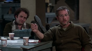 Movie still from “The Goodbye Girl” (1977), directed by Herbert Ross – A man sitting at a table in front of another man; Medium shot, High angle