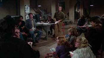 Movie still from “The Goodbye Girl” (1977), directed by Herbert Ross – A group of people sitting in a room with papers; Wide shot, High angle