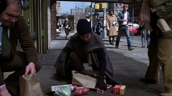 Movie still from “The Goodbye Girl” (1977), directed by Herbert Ross – A person sitting on the ground with a bag of food; Wide shot, Low angle