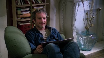 Movie still from “The Goodbye Girl” (1977), directed by Herbert Ross – A man sitting on a couch holding a laptop; Medium shot, Low angle