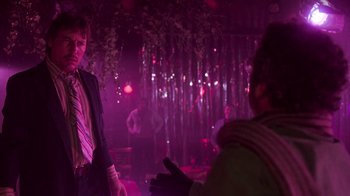 Movie still from “The Goodbye Girl” (1977), directed by Herbert Ross – A man wearing a suit and tie standing in front of a crowd; Medium shot, Over the shoulder angle