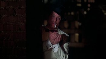 Movie still from “The Goodbye Girl” (1977), directed by Herbert Ross – A man wearing a top hat smoking a cigarette; Close Up shot, Over the shoulder angle