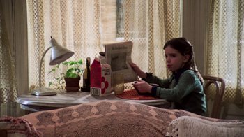 Movie still from “The Goodbye Girl” (1977), directed by Herbert Ross – A young girl sitting at a table reading a newspaper; Medium shot, High angle