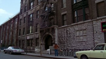 Movie still from “The Goodbye Girl” (1977), directed by Herbert Ross – A man standing on the side of a brick building; Extreme Wide shot, Low angle
