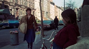Movie still from “The Goodbye Girl” (1977), directed by Herbert Ross – A woman walking down a street with a bicycle; Wide shot, Over the shoulder angle