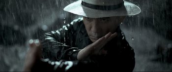 Movie still from “The Grandmaster” (2013), directed by Kar-Wai Wong – A man wearing a hat is standing in the rain; Close Up shot, Low angle