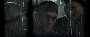 Movie still from “The Grandmaster” (2013), directed by Kar-Wai Wong – A person wearing a hat in the rain; Close Up shot, Over the shoulder angle