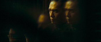 Movie still from “The Grandmaster” (2013), directed by Kar-Wai Wong – A person's face with a dark background; Close Up shot, Over the shoulder angle